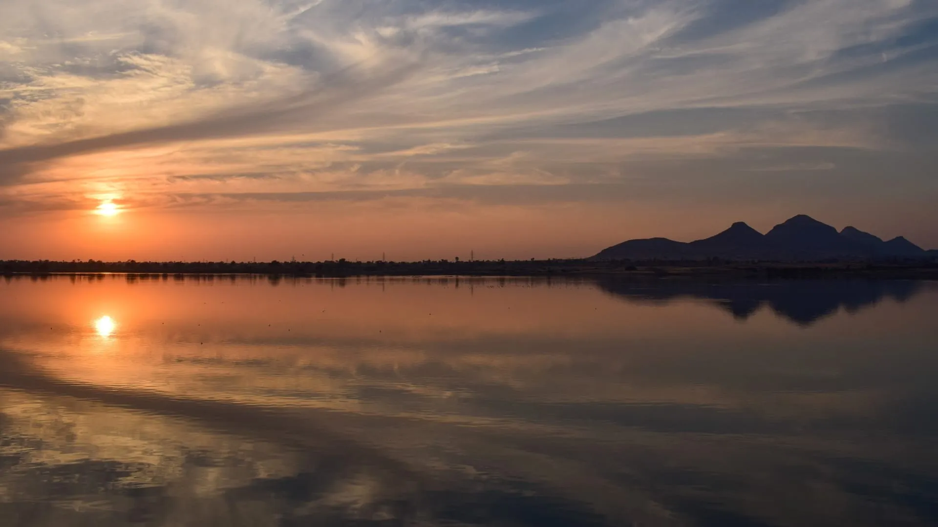 A low sun over still water throwing a long broken reflection towards the camera.