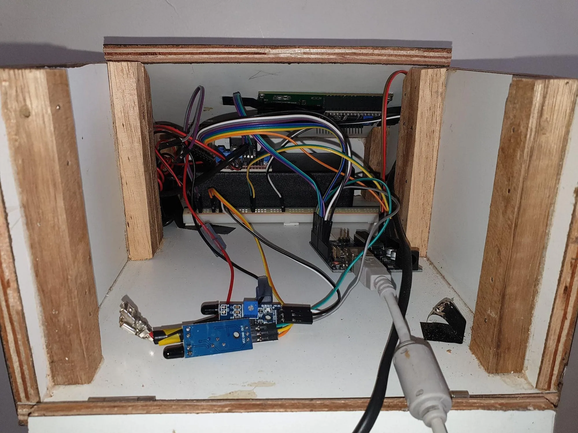 The open wooden enclosure of the first version, showing an Arduino, a motor driver and hand-run wiring in several colours.